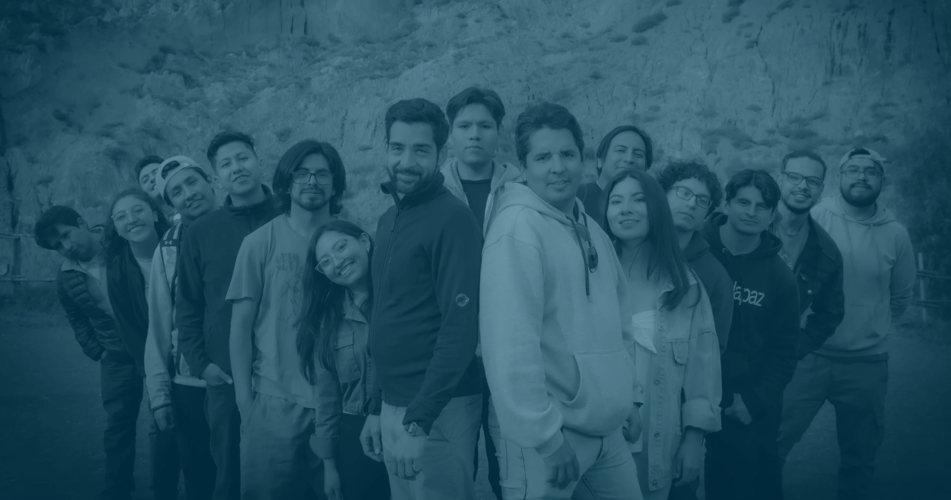 A group of people standing together, smiling and posing for a photo. They are dressed in various clothing styles